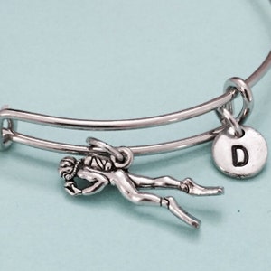 Op de afbeelding: Een zilveren armband met een zilveren bedel van een duiker en een zilveren bedel met de letter D.