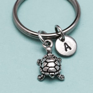 May include: Silver turtle keychain with a silver charm with the letter A on it.