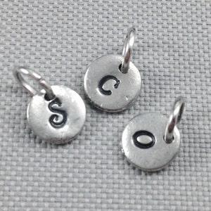 May include: Three silver charms with letter initials C, S, and O. Each charm has a small loop for attaching to a necklace or bracelet.