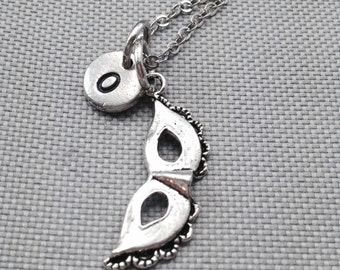 May include: Silver necklace with a silver initial charm and a silver masquerade mask charm.