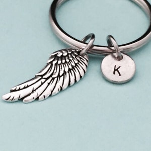 以下が含まれることがあります： 銀色の天使の羽根のキーホルダーと、Kの文字が刻まれた銀色のチャーム