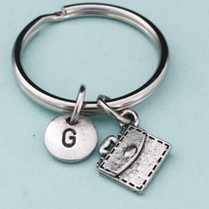 May include: Silver keychain with a silver letter G charm and a silver briefcase charm.