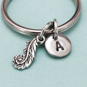 May include: Silver keychain with a feather charm and a round charm with the letter A engraved on it.