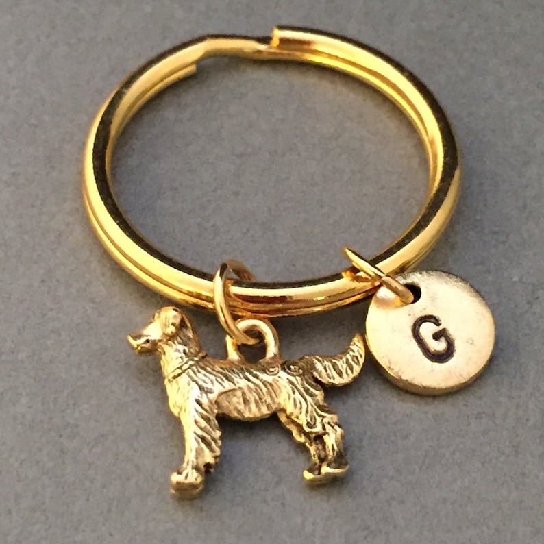 May include: Gold-toned keychain with a golden dog charm and a round charm with the letter "G" engraved on it.