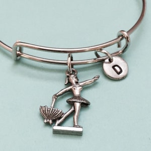 May include: A silver charm bracelet with a ballerina charm and a letter 'D' charm.