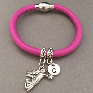 May include: A pink leather bracelet with a magnetic clasp, two silver spacer beads, a silver angel charm, and a silver charm with the letter "C".