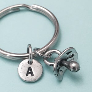 May include: Silver keychain with a pacifier charm and a round charm with the letter A.