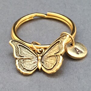 May include: Gold-toned butterfly keychain with a round gold-toned charm with the letter 'A' engraved on it.
