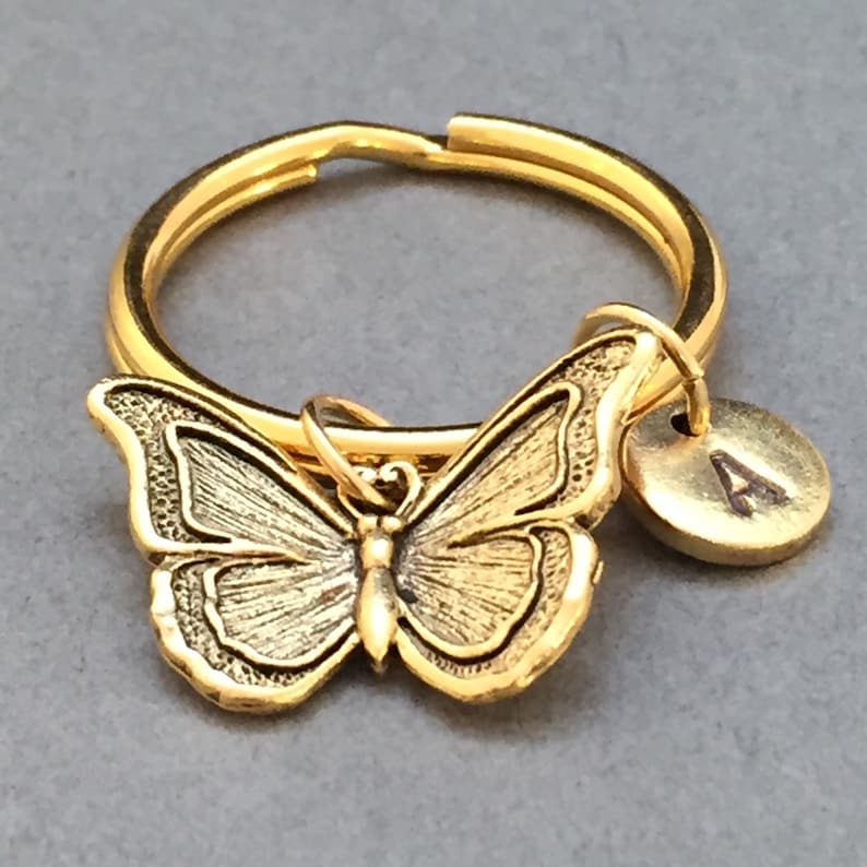May include: Gold-toned butterfly keychain with a round gold-toned charm with the letter 'A' engraved on it.