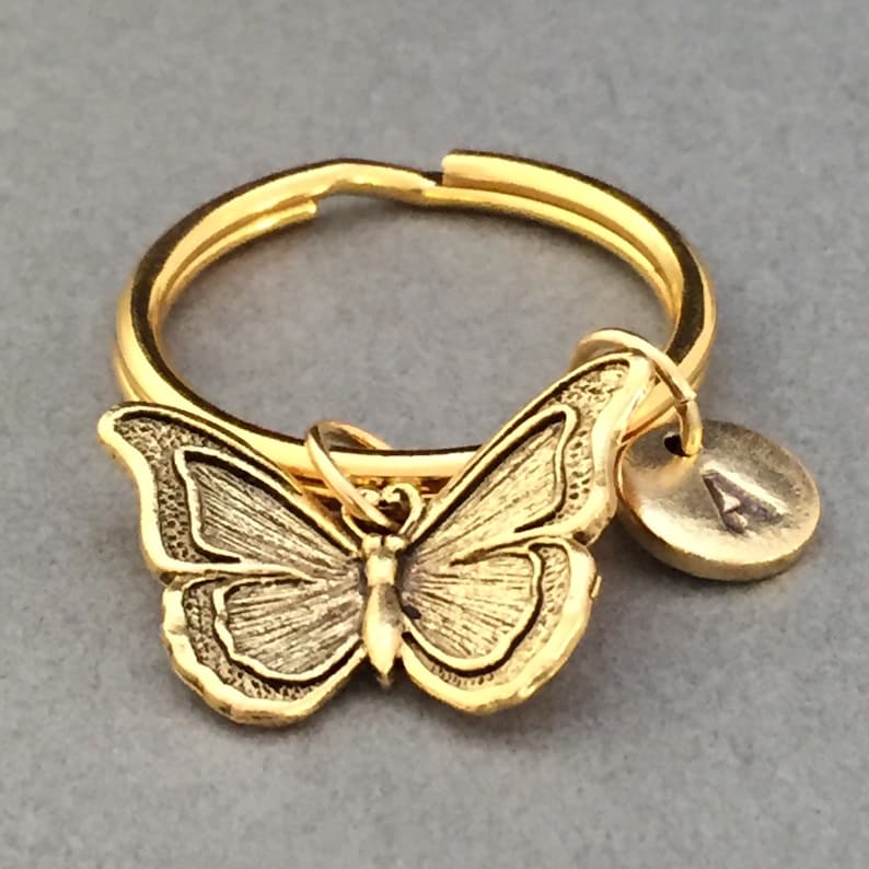 May include: Gold-toned butterfly keychain with a round charm engraved with the letter "A".