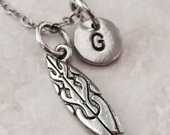 May include: Silver necklace with a surfboard charm and a round charm with the letter G.