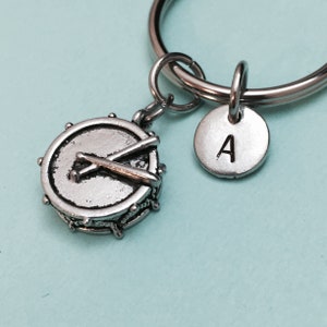 May include: Silver keychain with a drum and drumsticks charm and a silver charm with the letter A.