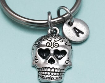 May include: Silver keychain with a sugar skull charm and a silver charm with the letter A.