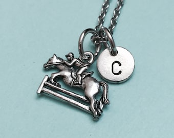 May include: Silver necklace with a horse jumping over a hurdle charm and a silver disc charm with the letter C.