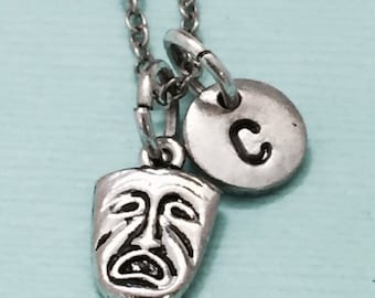 May include: A silver necklace with a silver charm of a crying theater mask and a silver charm with the letter C.