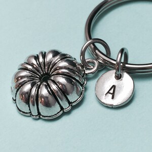 May include: Silver keychain with a small cake pan charm and a round charm with the letter A.