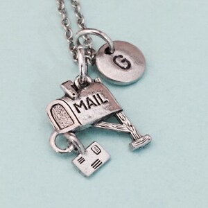 May include: Silver necklace with a mailbox charm, a small envelope charm, and a letter 'G' charm. The mailbox charm has the word 'MAIL' on it.
