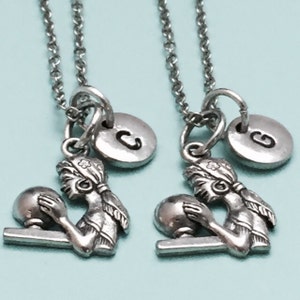 May include: Two silver necklaces with a bowling pin charm and a silver initial disc. The initial discs are C and G.