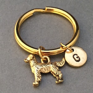 May include: Gold-toned keychain featuring a small golden dog charm and a round disc charm with the letter "G" engraved on it.