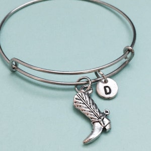 May include: Silver charm bracelet with a boot charm and a charm with the letter D.