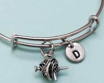 Op de afbeelding: Zilveren armband met een garenbal en breinaalden bedel en een zilveren bedel met de letter D.