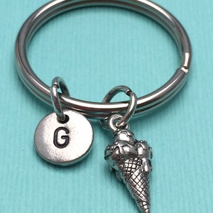May include: Silver keychain with a letter G charm and a silver ice cream cone charm.