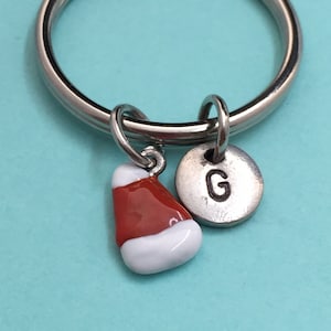 May include: A silver key chain with a red and white Santa hat charm and a silver charm with the letter G.