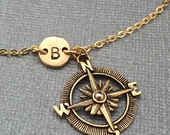 May include: Gold necklace with a compass charm and a small round charm with the letter "B" engraved on it.