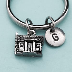 以下が含まれることがあります： 小さな家のチャームと、Gの文字が刻まれた銀色の円盤チャームが付いた銀色のキーホルダーです。