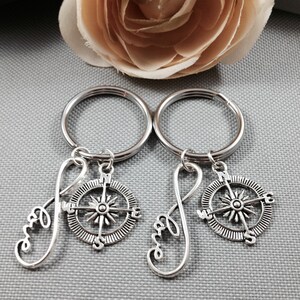 May include: Two silver keychains with infinity symbols and compass charms. The infinity symbols are inscribed with the word "love".