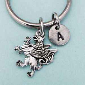May include: Silver keyring with a griffin charm and a silver disc charm with the letter A.