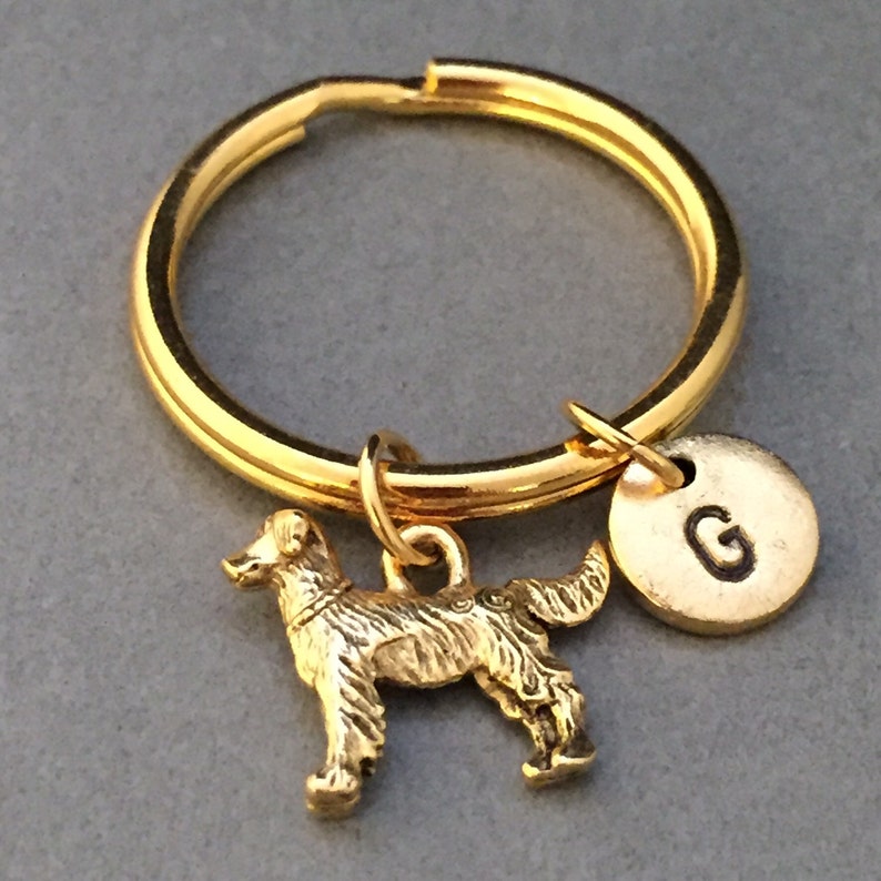May include: Gold-toned keychain with a golden dog charm and a round charm with the letter "G" engraved on it.