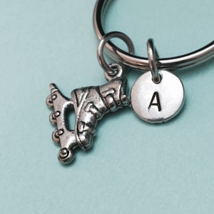 Op de afbeelding: Zilveren rolstoelschijf-bedel met een zilveren initialenbedel met de letter "A" bevestigd aan een zilveren sleutelhanger.