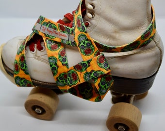 Puede incluir: Patín de ruedas blanco con correas de patrón naranja, verde y rojo. Las correas están decoradas con un diseño de calavera y flores y el texto "My Hungry Rhino Skaters".
