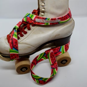 May include: White roller skates with watermelon print straps. The straps are attached to the skates with velcro. The text "My Hungry Pine Studio" is printed on the strap.