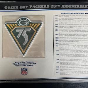 Puede incluir: Un parche del 75 aniversario de los Green Bay Packers de la temporada de 1993. El parche es un triángulo verde, dorado y plateado con el logotipo de los Packers y el número 75. El parche se muestra en una funda protectora transparente con texto.