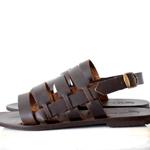 May include: Brown leather sandals with a woven strap design and an adjustable ankle strap with a gold buckle.