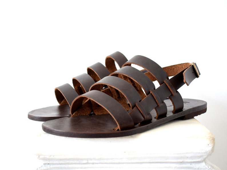 May include: Brown leather sandals with a woven strap design and an ankle strap with a buckle closure.