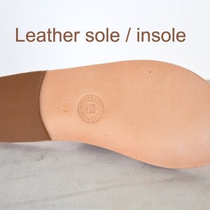 May include: A light brown leather shoe sole with a textured heel and a smooth, rounded toe. The text "Leather sole / insole" is at the top. A circular stamp is visible near the center of the sole.