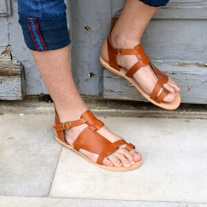 K&ouml;nnte beinhalten: Braune Ledersandalen mit Schnallenverschluss und Zehenriemen. Die Sandalen haben ein schlichtes Design und sind aus hochwertigem Leder gefertigt.