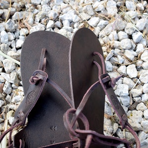 May include: A pair of brown leather sandals with adjustable straps. The sandals have a simple design and are made of high-quality leather.