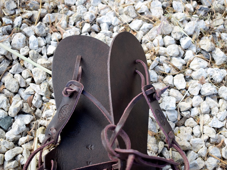 May include: A pair of brown leather sandals with adjustable straps. The sandals have a simple design and are made of high-quality leather.
