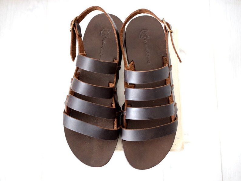 May include: A pair of brown leather sandals with multiple straps. The sandals have a simple design and are made of high-quality leather.