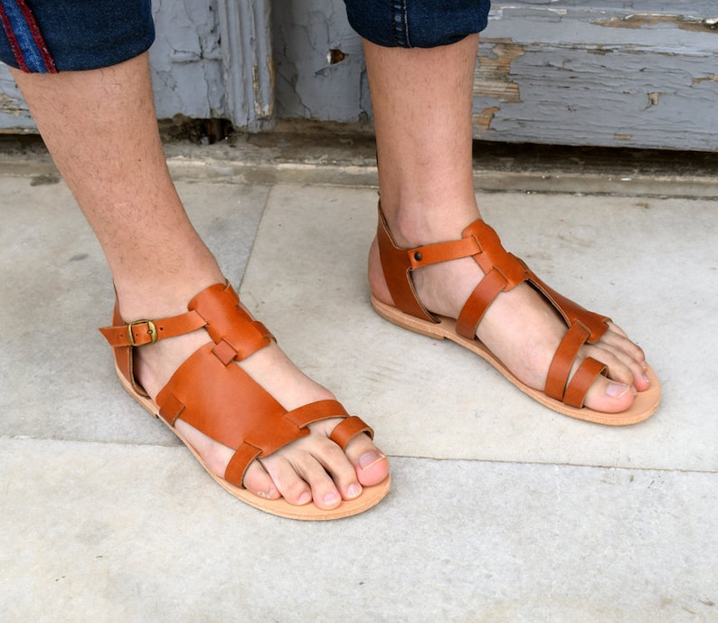 K&ouml;nnte beinhalten: Braune Ledersandalen mit Schnallenriemen und Zehenschlaufe. Die Sandalen haben ein schlichtes Design und sind aus hochwertigem Leder gefertigt.