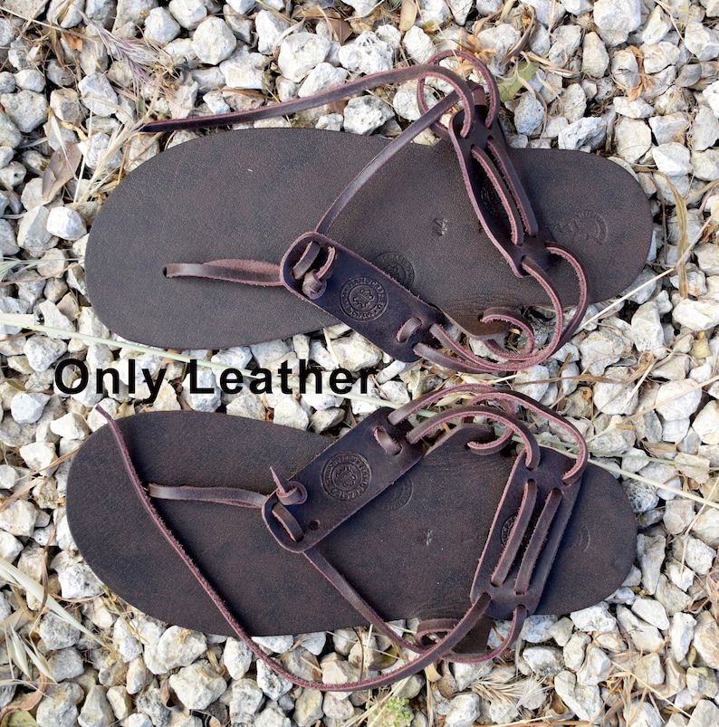 May include: A pair of brown leather sandals with laces that wrap around the ankle. The sandals have a simple design and are made of high-quality leather.