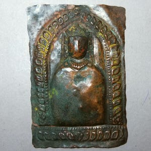May include: A rectangular, weathered bronze relief sculpture depicting a figure within an arched frame. The figure has a crown and ornate necklace. The relief has a patina of green and brown hues, suggesting age and exposure to the elements.