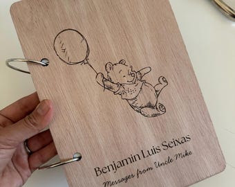 May include: A rectangular light-colored wooden notebook cover featuring a laser-engraved illustration of a bear holding a balloon. The text reads Benjamin Luis Seixas, Messages from Uncle Mike. The cover is bound with two silver metal rings.
