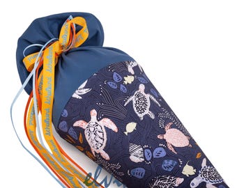 May include: A navy blue school cone with a sea turtle pattern. The cone is decorated with orange and blue ribbons and the text "Schulkind". The cone is designed to hold school supplies.