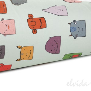 May include: A light green fabric with a repeating pattern of colorful cartoon monster faces. The monsters have different expressions and features, including horns, teeth, and eyes.