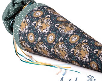 May include: A green and white fabric cone with a tiger and sun pattern. The cone has a white polka dot pattern on the top and a green polka dot pattern on the bottom. The cone is decorated with a blue, yellow, and green ribbon.